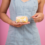 Girl holding a small wavy daisy tag a long key ring. Pink background.