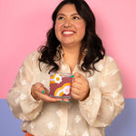 Girl holding a wavy daisy pattern glass mug. Pink and purple background.