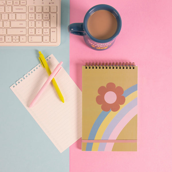 Rainbow flower taskpad on a pink and blue background with a diner mug and misc items.