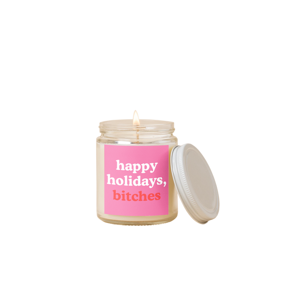 8 oz candle jar with pink label on front with text that reads "happy holidays, bitches" in white and red letters.