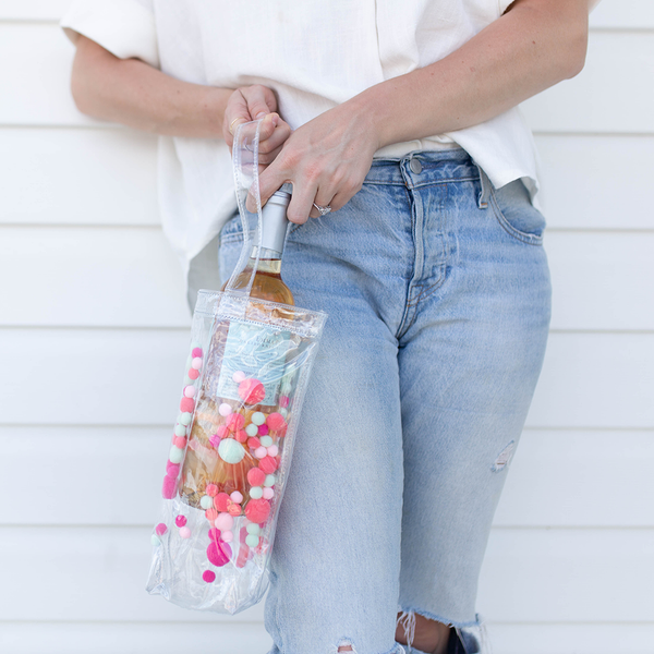 Cute wine tote bag in clear vinyl with colorful pom poms.