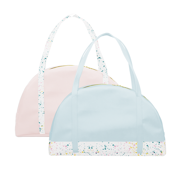 Two travel tote bags, one powder blue with white paint splatter detail along the bottom and one blush pink with white paint splatter straps.