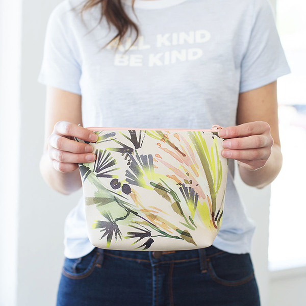 Girl holding a cute cosmetics bag in a tropical leaves pattern.