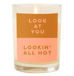 A candle with a decal that says "Look at you lookin' all hot" printed on. Top half color of the decal is light brown and the bottom half is a dusty pink. 