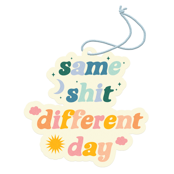 "Same Shit Different Day" air freshener with cool tone and warm letter print including stars, moon, sun, and clouds around.