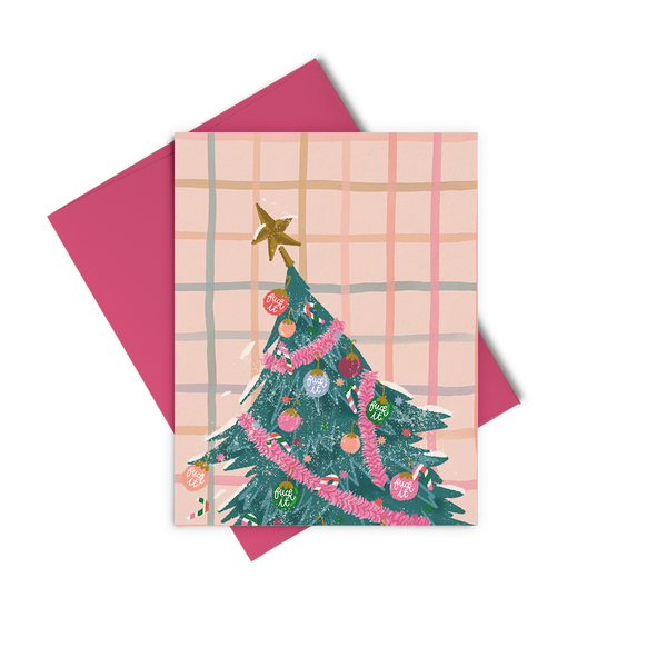 A pink holiday greeting card with a slanted Christmas tree in pink decorations and "fuck it" ornaments