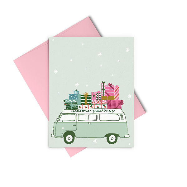 Light green snowy card with a green "seasons greetings" van with colorful presents on top of it