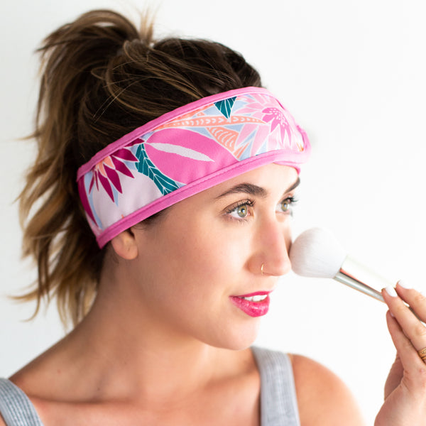 A multicolored, floral designed spa head wrap displayed on a person doing their makeup.