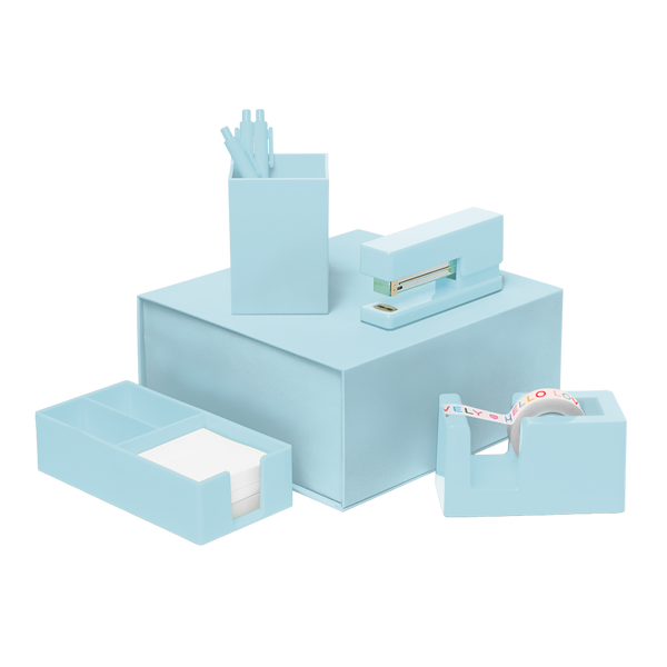 Powder blue desk set including a stapler, tape dispenser, utility tray, and pen cup with three powder blue pens all stacked on top of a matching light blue box.