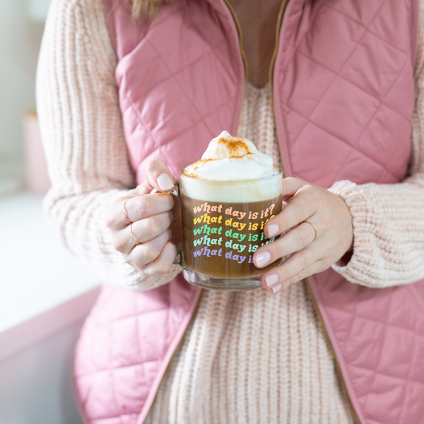 a girl holding a cute glass mug that says what day is it