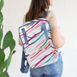 Lady holding colorful striped everyday backpack over her shoulder.