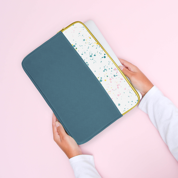 Hands holding a spruce splatter laptop sleeve.