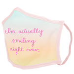 A pastel ombre facemask with pink cursive script saying "I'm actually smiling right now." 