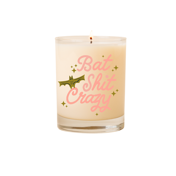 Candle rocks glass with text that reads "Bat Shit Crazy" in pink font; olive colored animated bat and minimalist sparkle stars surround the text