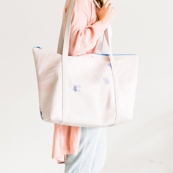 Girl wearing slippers holding a cute travel bag in light purple with an abstract floral design.