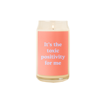 A 16 oz. candle with a coral decal on it with the phrase "It's the toxic positivity for me" printed on.