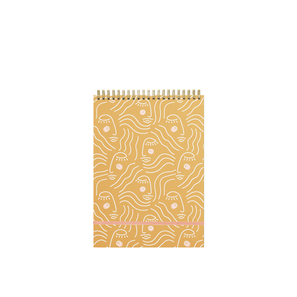 A golden yellow task notebook with a stencil female face design in white lining.