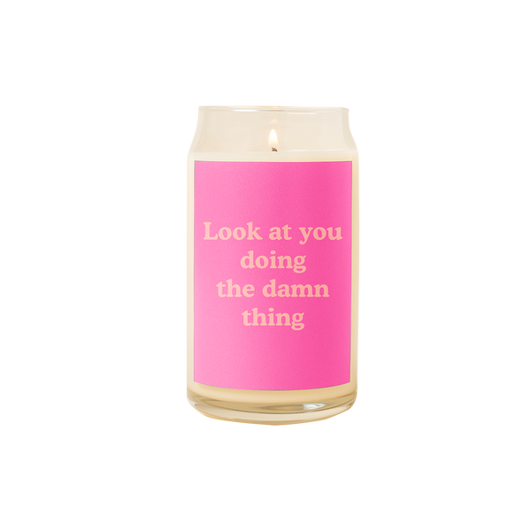 A 16 oz. candle with a pink decal on it with the phrase "Look at you doing the damn thing" printed on.