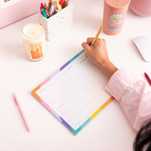 Girl writing on the large rising scallop tearaway notepad along with misc items