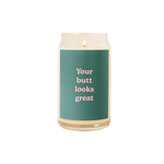 A 16 oz. candle with a green decal on it with the phrase "Your butt looks great" printed on.