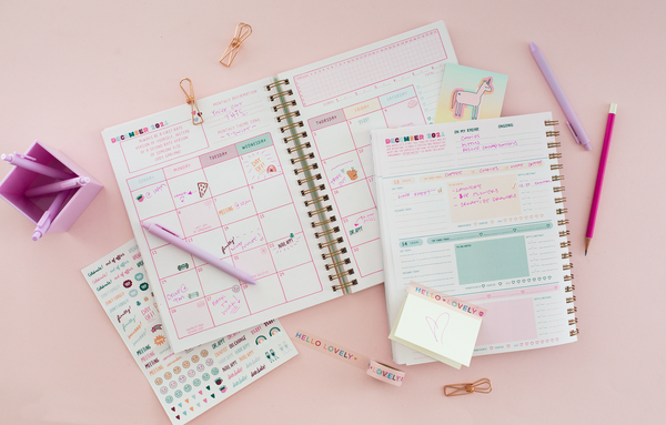 Jotter pens and pencil displayed on two different planners and a sticker sheet. Desk organizer is on the left side with more Lilac Jotter pens in the organizer.