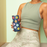 A girl in green holding an dark blue 16 oz. tumbler with rainbow flowers on it.