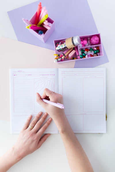 Blush Pink Jotter pen writing in a planner. Desk organizers displayed over planner with stationary and other Jotter pens in the desk organizers.